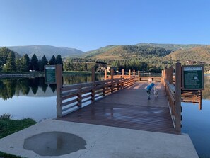 A wooden boardwalk leading to a dock over a calm lake, surrounded by mountains and trees. - New Upscale Remodeled 2 Bedroom Base of Beaver Creek! (Avon)