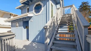 A wooden deck with a staircase leading to a building with a blue exterior and a number '139' visible. - Casa Azul Steps from Rio del Mar Beach (Aptos)