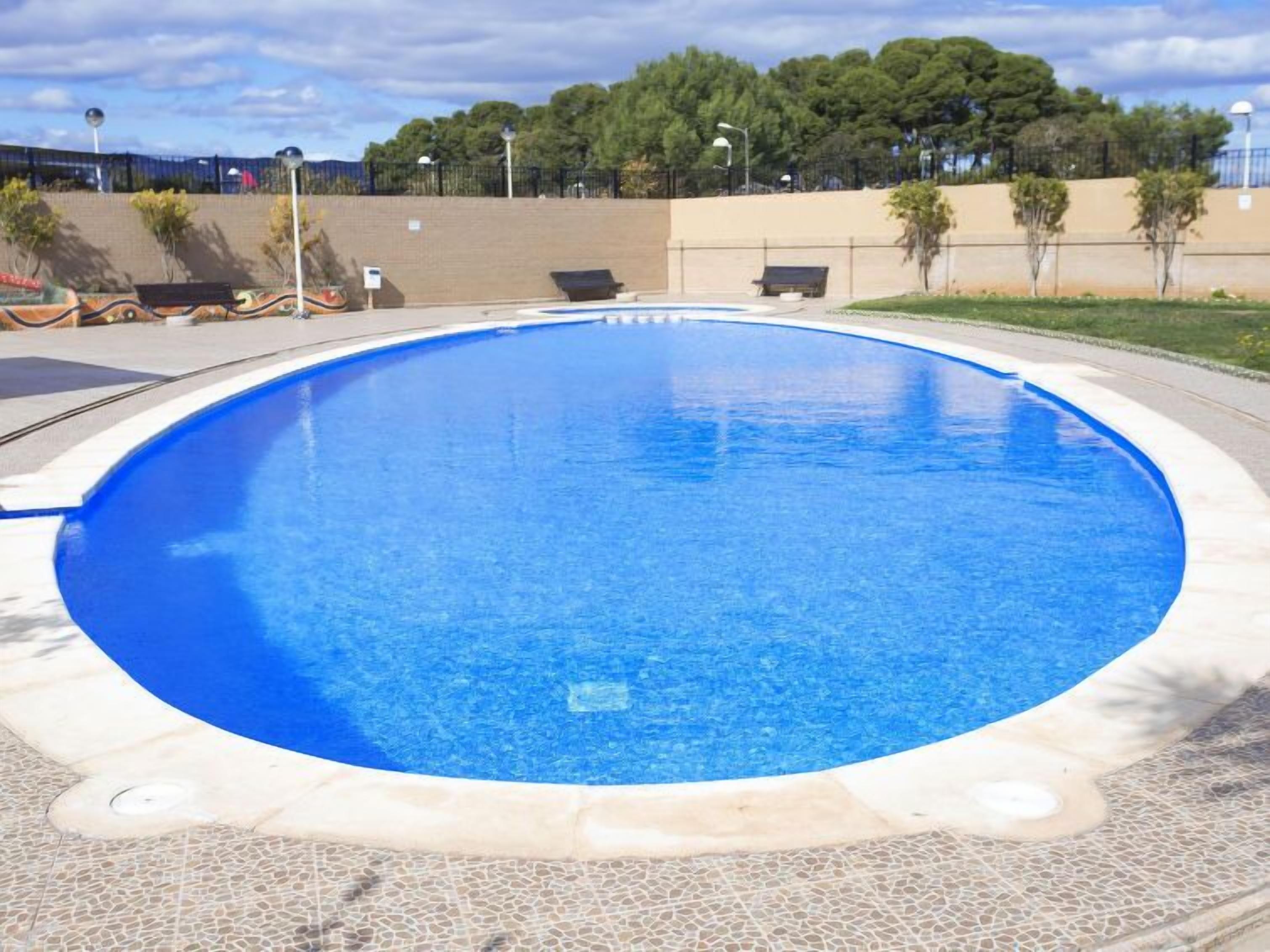 A circular swimming pool with a clear blue water surface, surrounded by a tiled deck.