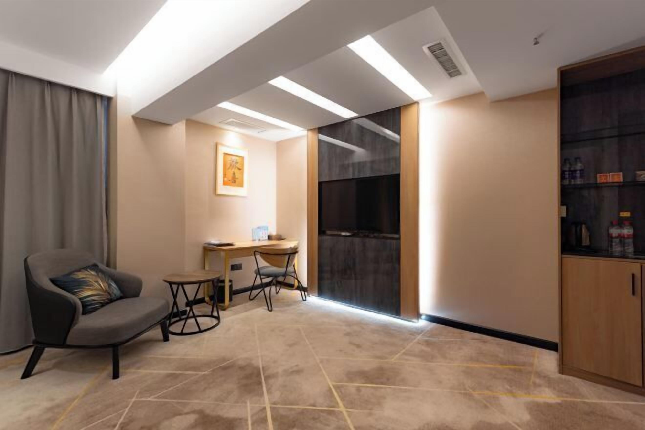 A modern hotel room with a sofa, a small table, a desk, and a cabinet.
