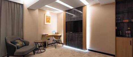 A modern hotel room with a sofa, a small table, a desk, and a cabinet.