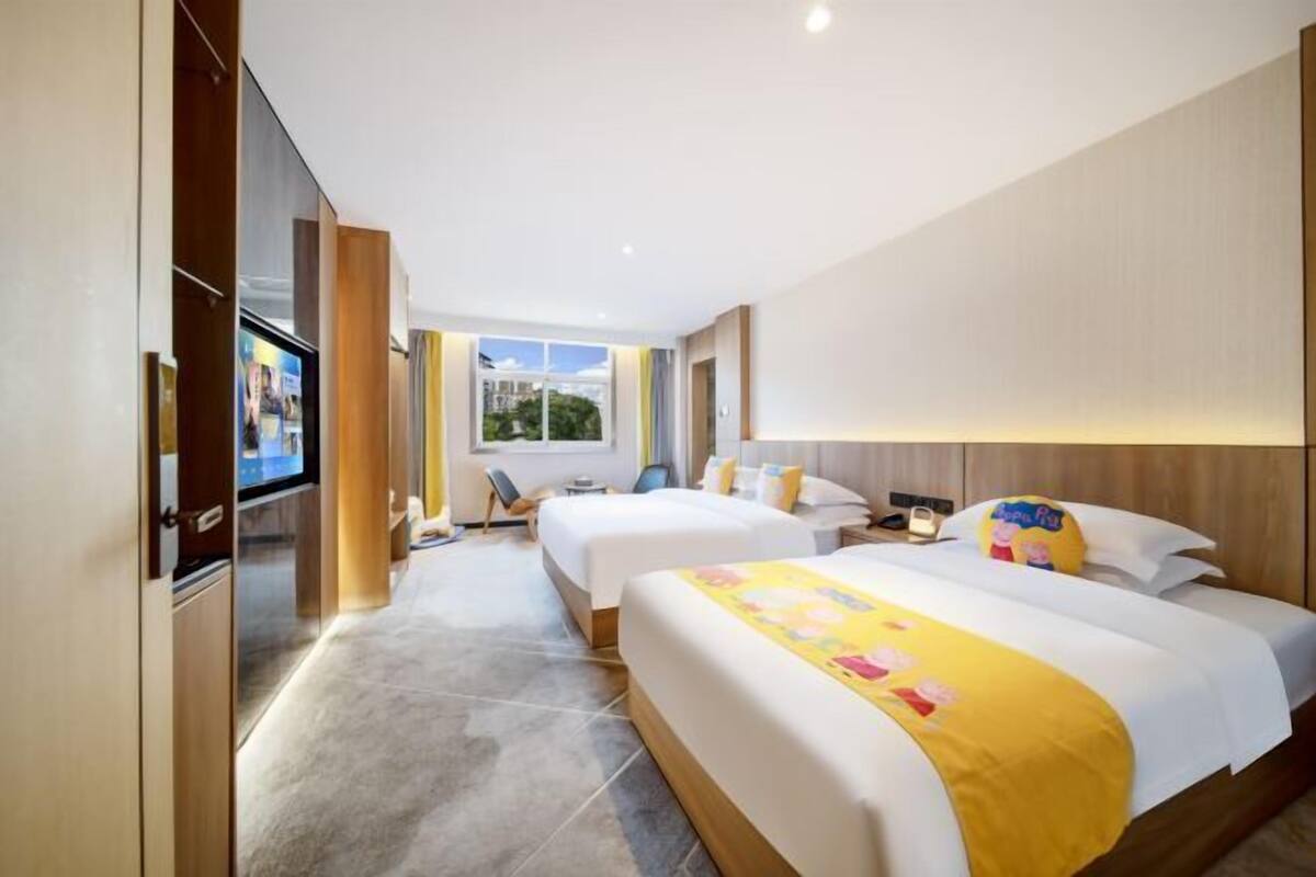Une chambre d’hôtel avec deux lits, une télévision, une fenêtre et une salle de bain.