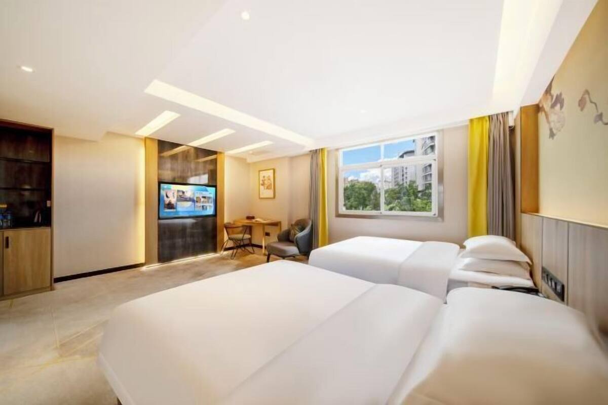 Une chambre d’hôtel avec deux lits, un bureau, une télévision et une fenêtre donnant sur la ville.