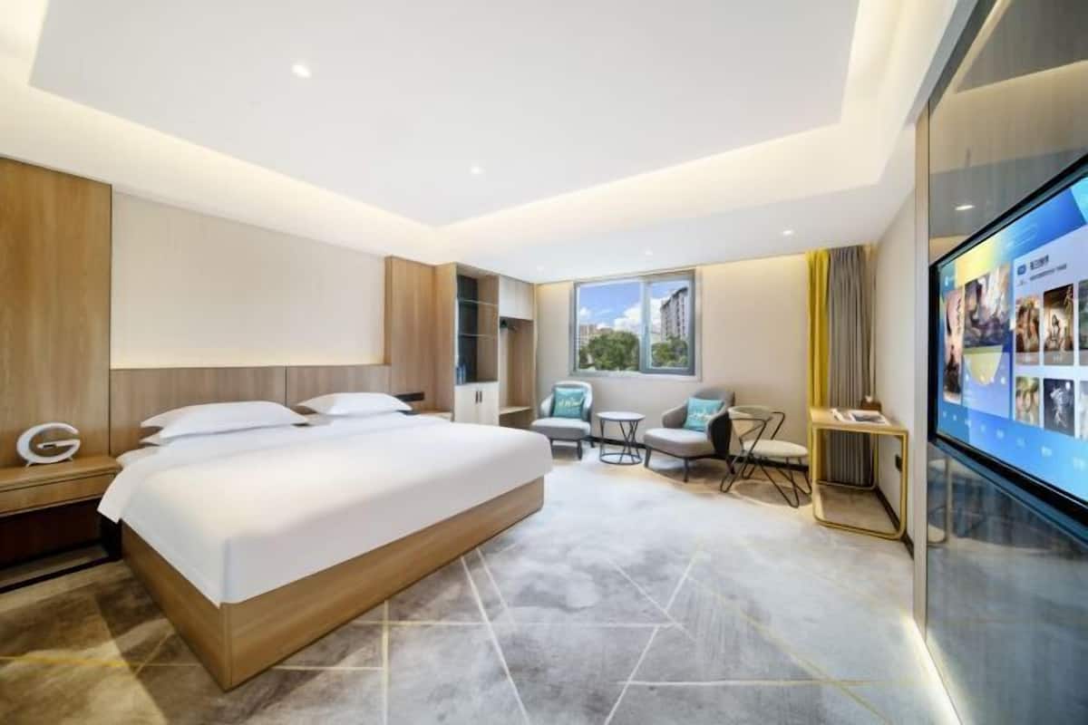 Une chambre d’hôtel moderne équipée d’un grand lit, d’un bureau, d’une petite table et d’un coin salon avec des fauteuils.