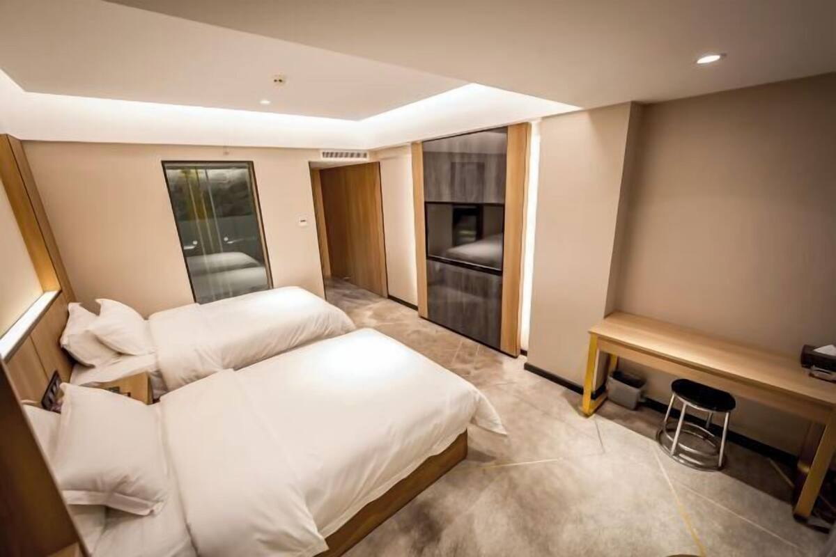 Une chambre d’hôtel moderne équipée de deux lits, d’un bureau et d’un coin salon.