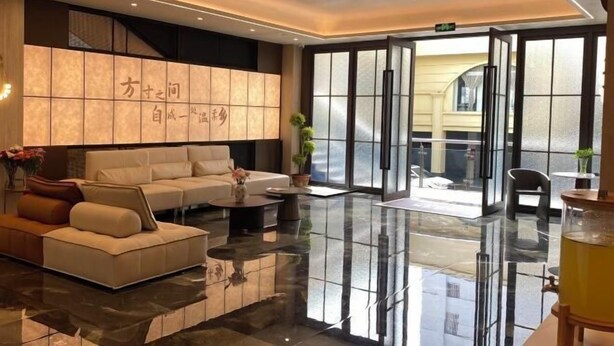 A modern lobby with a seating area, a reception desk, and a large glass door leading outside. - Hongsheng Hotel (Yuxi)