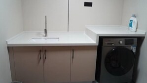 A compact bathroom with a sink, mirror, and washing machine. - Hongsheng Hotel (Yuxi)