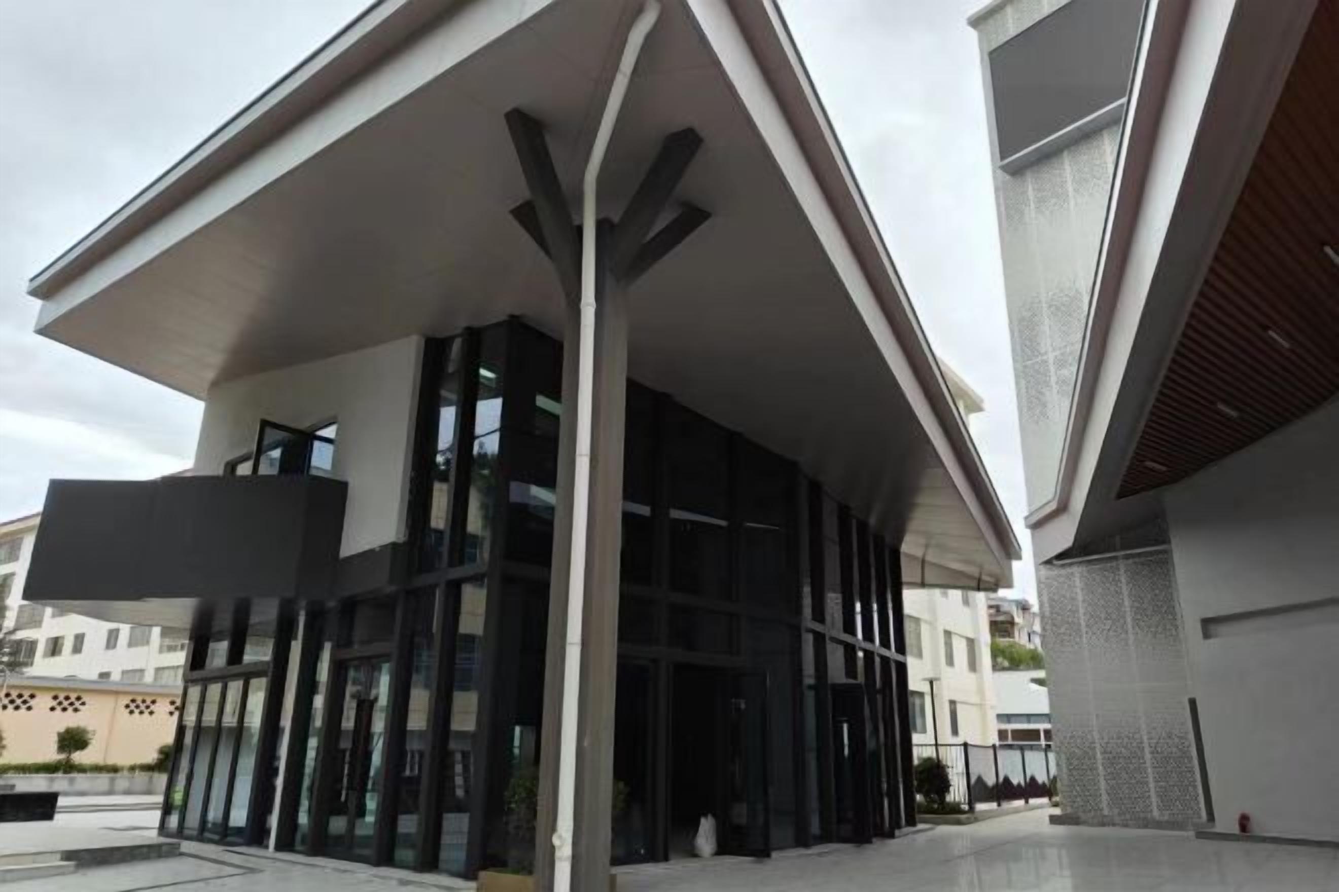 A modern building with a flat roof, large glass windows, and a central entrance.