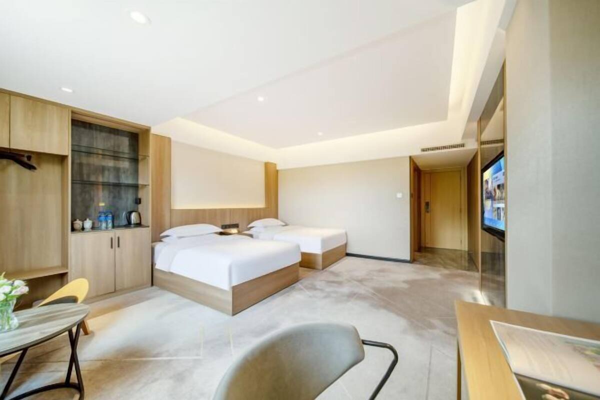 Une chambre d’hôtel avec deux lits, un bureau, une chaise, une télévision et un mini-bar.