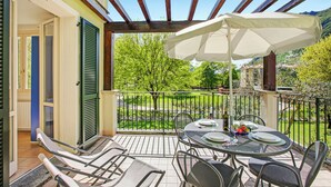Eine überdachte Terrasse im Freien mit Esstisch, Stühlen und einem großen Sonnenschirm.