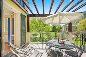 A covered outdoor patio with a table set for dining, chairs, and a large umbrella. - Porto Letizia Orchidea 4, Porlezza, Italy (Porlezza)