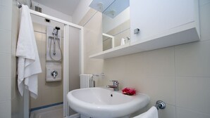 Ein modernes Badezimmer mit Dusche, Waschbecken und Spiegel.