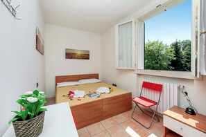 A bedroom with a bed, a chair, a desk, a window, and a plant. - Porto Letizia Mimosa 4, Porlezza, Italy (Porlezza)