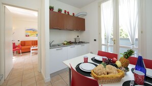 Eine moderne Küche mit weißen Schränken, einem Esstisch mit Stühlen und einer Frühstücksvorrichtung mit Früchten und Brot.