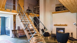 Ein geräumiger Loft mit Holztreppe, Kamin und modernen Möbeln.