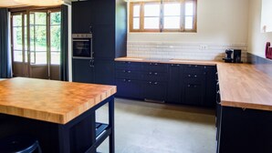 Eine moderne Küche mit dunklen Schränken, einer Holz Arbeitsplatte und einem großen Fenster.