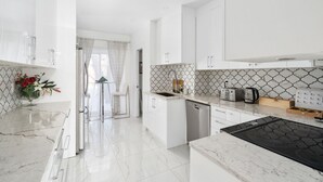 A modern kitchen with white cabinetry, a black stove top, and a tiled backsplash.