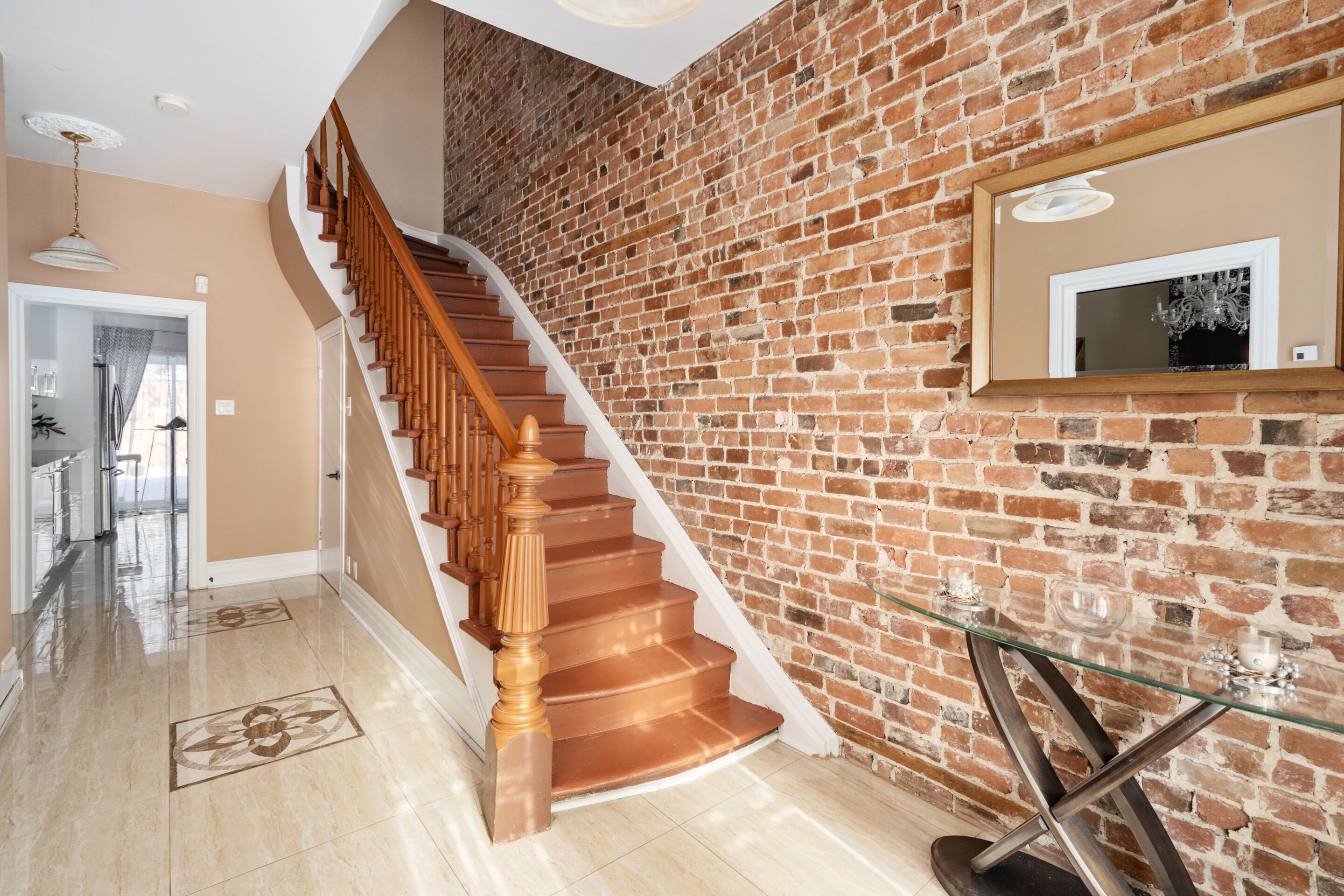 A staircase with wooden steps and a glass table against a brick wall.
