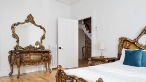 A bedroom with a large ornate bed, a matching dresser, and a mirror.