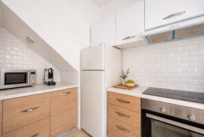 A modern kitchen with a microwave, refrigerator, stove, and wooden cabinets.