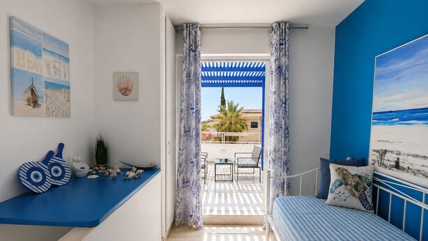 A bedroom with a bed, a seating area with a table, and a balcony with a view.