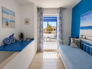 A bedroom with a bed, a seating area with a table, and a balcony with a view.