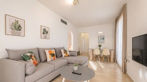 A modern living room with a grey sofa, a coffee table, and a TV on the wall.