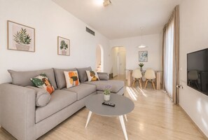 A modern living room with a grey sofa, a coffee table, and a TV on the wall.