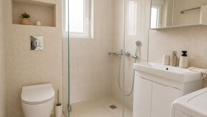 A modern bathroom with a toilet, shower, and sink.