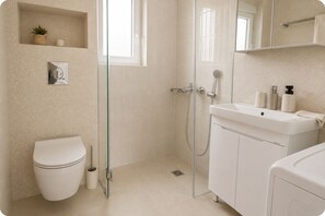 A modern bathroom with a toilet, shower, and sink.
