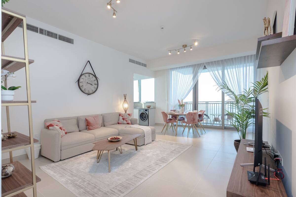 Een moderne woonkamer met een bank, salontafel en een eethoek met stoelen.
