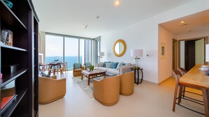 A spacious living area with a large window, a dining table, and a sofa. - EDEN'S Homes & Villas - 52/42 Emaar (Dubai)