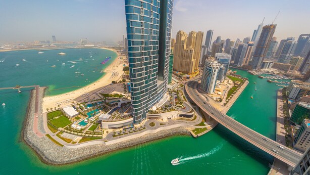 A high-rise hotel with a curved facade, a marina, and a beach. - EDEN'S Homes & Villas - 52/42 Emaar (Dubai)