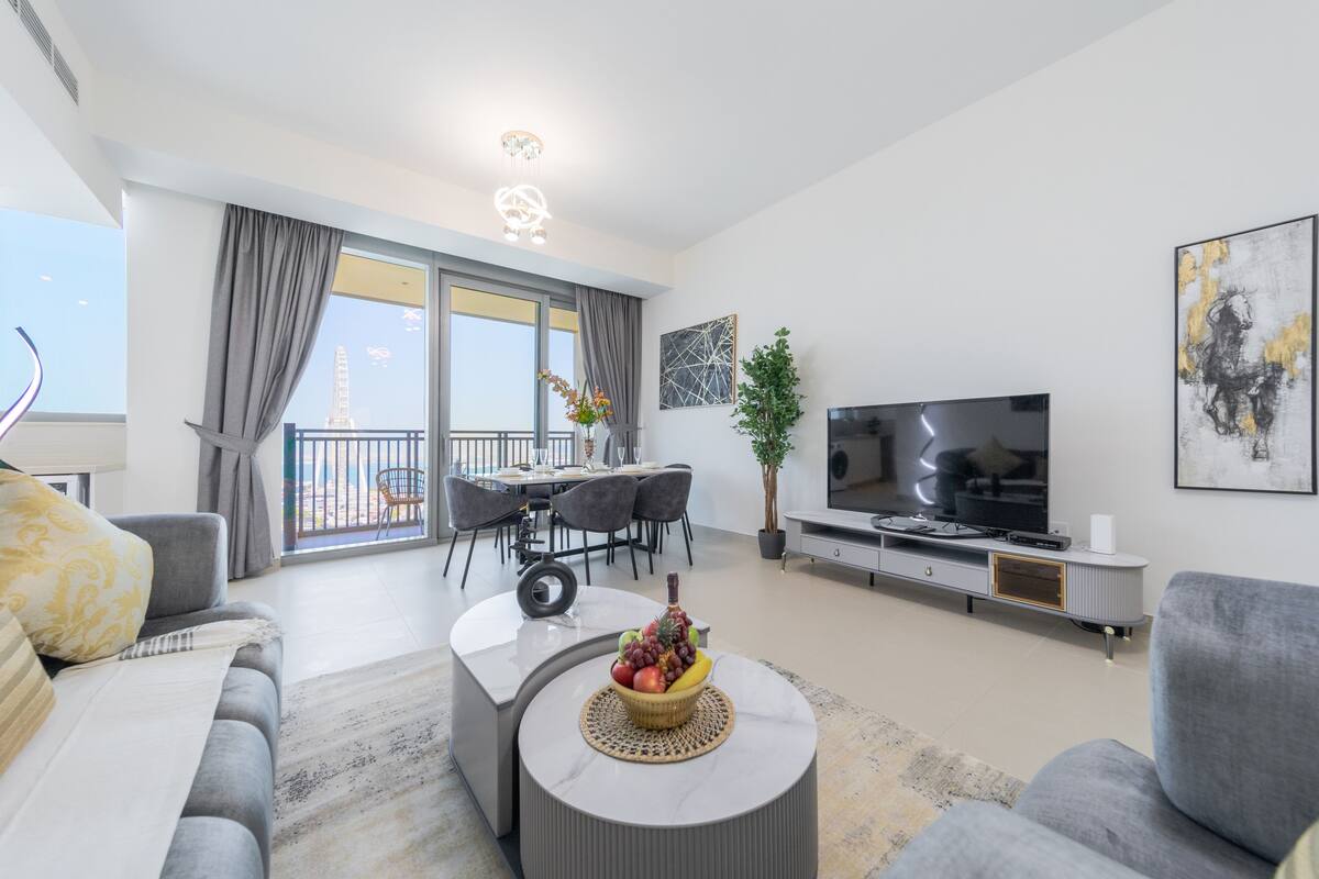 Een moderne woonkamer met een bank, salontafel, televisie en een eethoek met balkon.