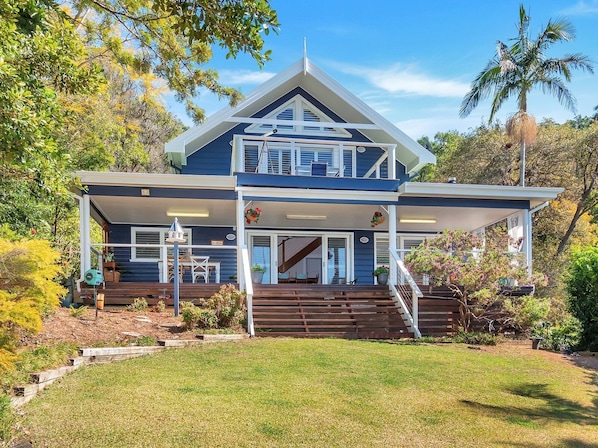 A two-story house with a balcony, a staircase leading to the upper floor, and a well-maintained garden.