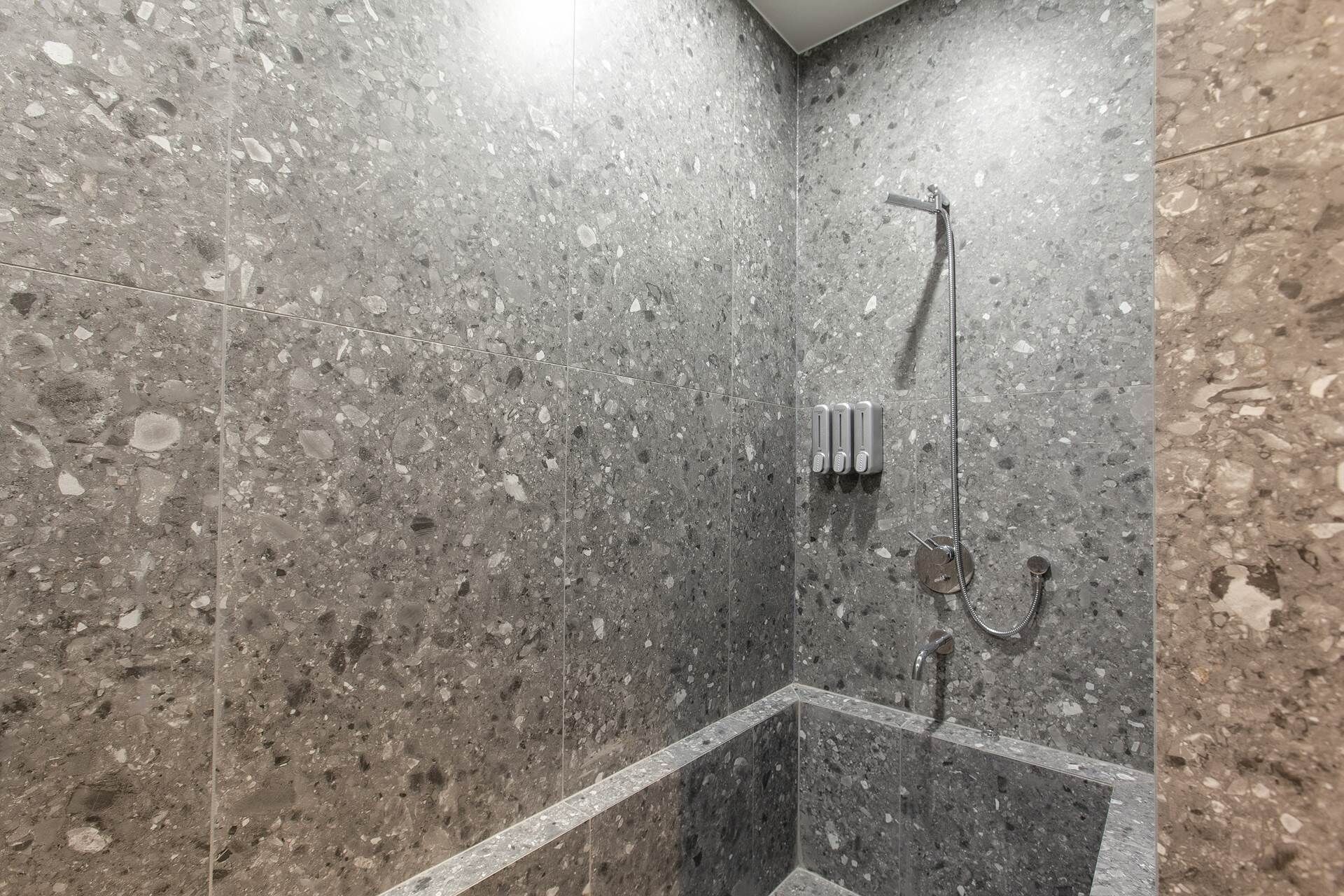 A modern shower with a glass enclosure and a handheld showerhead.