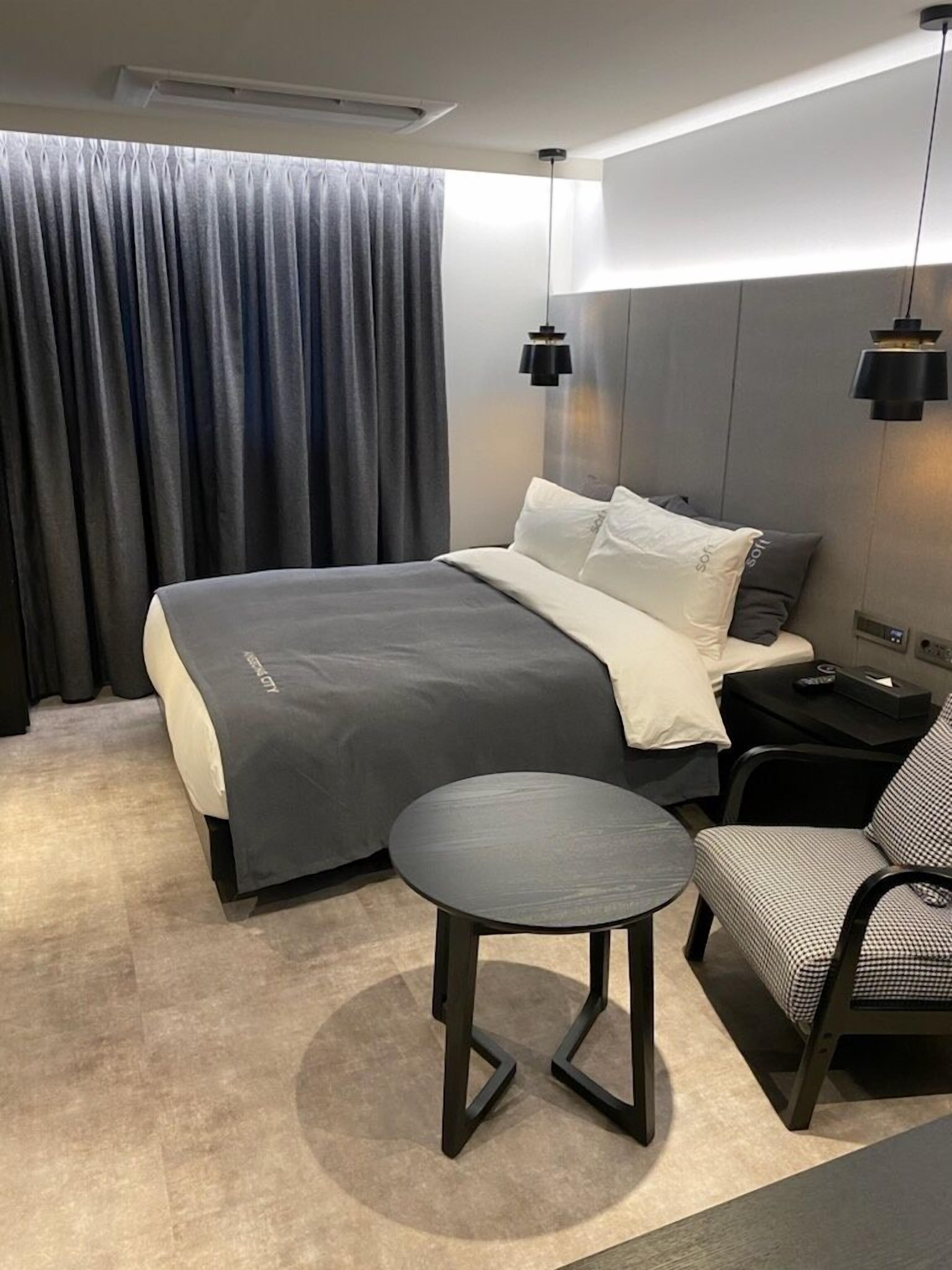 Une chambre d’hôtel moderne équipée d’un lit, d’une table de chevet, d’une chaise et d’une petite table ronde.