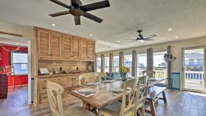 A spacious kitchen with wooden cabinets, a dining table set for four, and a ceiling fan. - Coastal Home: Walk to Holden Beach! (Holden Beach)