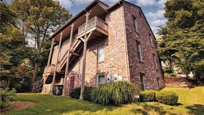 A two-story brick building with a balcony on the upper floor. - Trailside Manor - 0.5mi from UofA Campus! (Fayetteville)