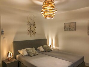A bedroom with a bed, two bedside tables, a wall-mounted dreamcatcher, and a ceiling light fixture. - Modern house with private pool near the beach (Oletta)