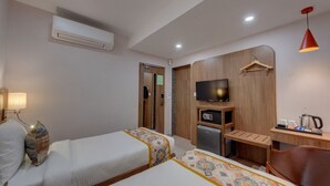 A hotel room with two beds, a TV, a desk with a kettle, and a wooden wardrobe. - The Beacon Hotel Vadodara (Vadodara)