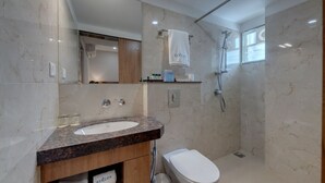 A modern bathroom with a marble sink, a toilet, a shower, and a large mirror. - The Beacon Hotel Vadodara (Vadodara)