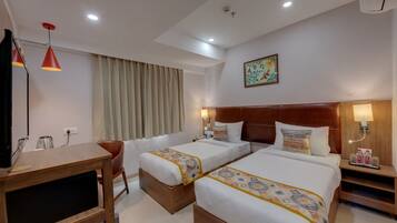 A hotel room with two beds, a desk, a chair, a TV, a lamp, and a window with curtains.
