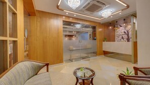 A lobby with wooden paneling, a reception desk, and a glass partition. - The Beacon Hotel Vadodara (Vadodara)