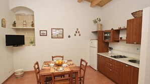A compact kitchen with wooden cabinets, a tiled backsplash, and a dining area with a table set for four.