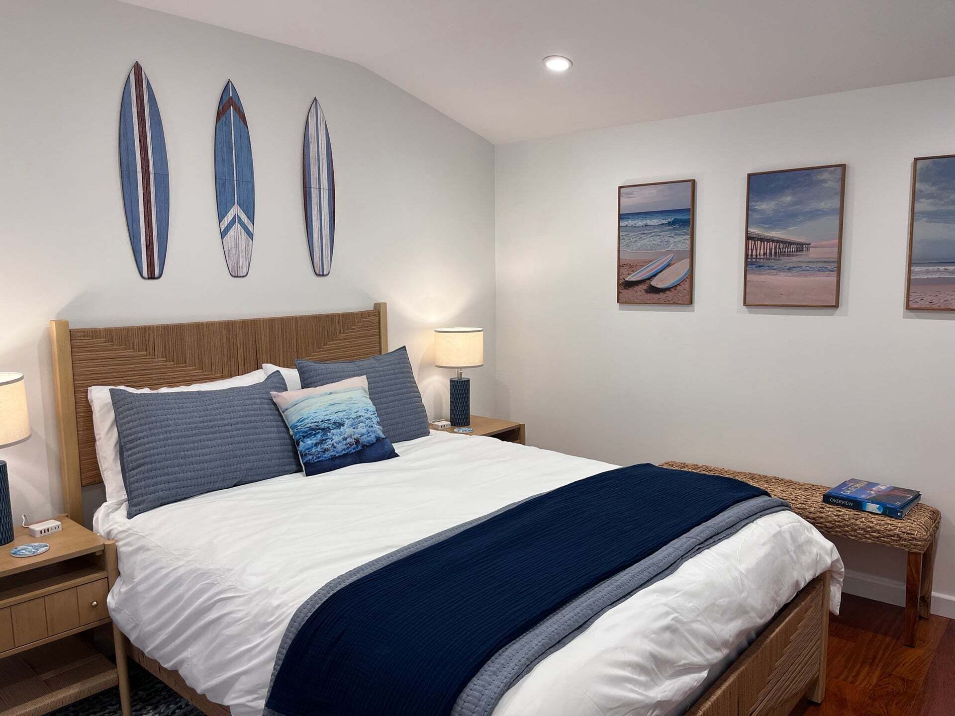 Quarto com cama, mesas de cabeceira, abajur e obras de arte nas paredes.