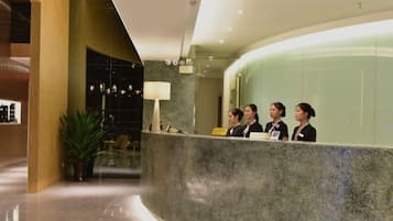 A reception area with a curved marble counter, a reception desk, and a seating area with chairs and a potted plant.