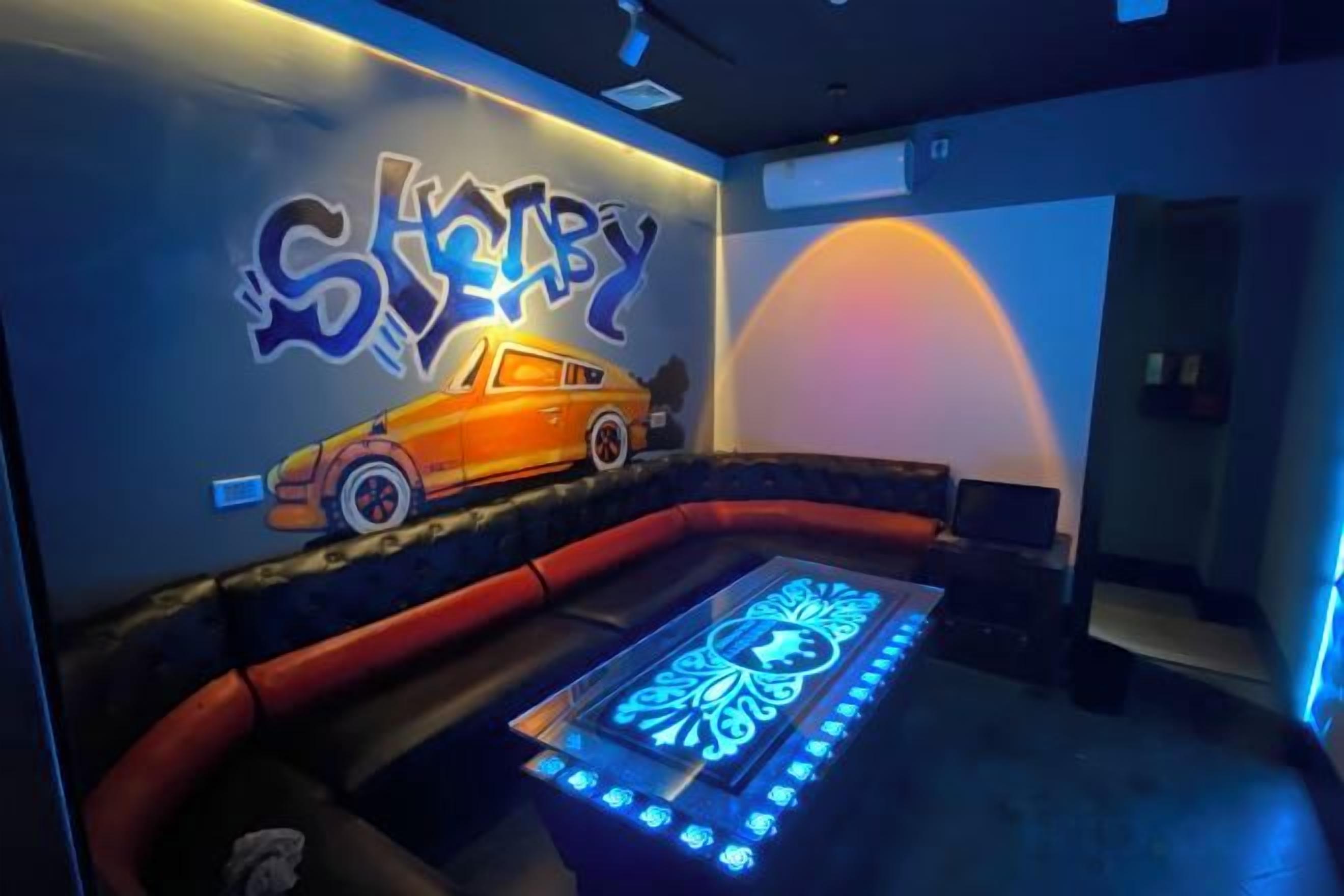 A room with a wall mural, a pool table, and a seating area.
