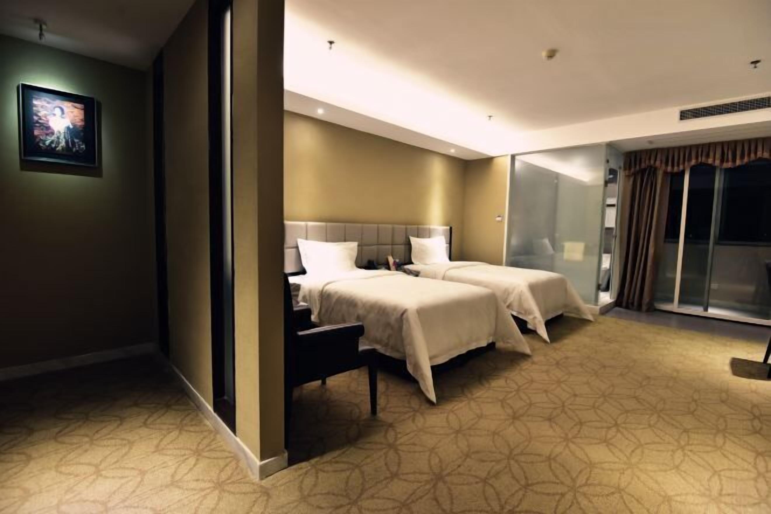 Une chambre d’hôtel avec deux lits, un grand miroir et une porte-fenêtre coulissante donnant sur un balcon.