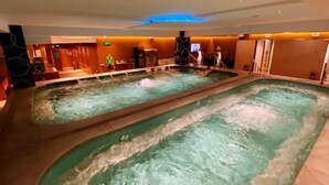 A large indoor swimming pool with multiple lanes, surrounded by a reception area and a bar. - Huasheng Holiday Hotel (Kaiping)